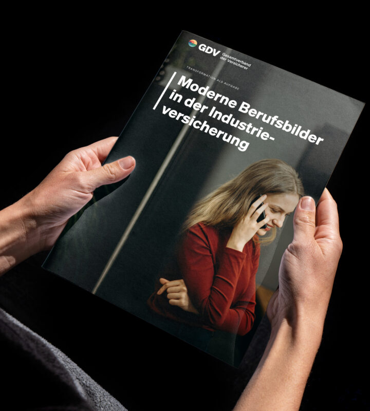 Zwei Hände halten die GDV-Broschüre „Moderne Berufsbilder in der Industrieversicherung“, auf dem Titel eine junge Frau am Telefon