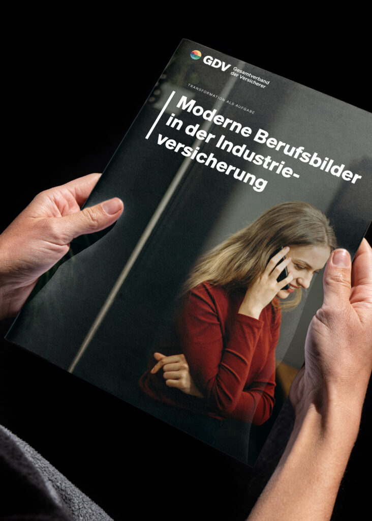 Zwei Hände halten die GDV-Broschüre „Moderne Berufsbilder in der Industrieversicherung“, auf dem Titel eine junge Frau am Telefon